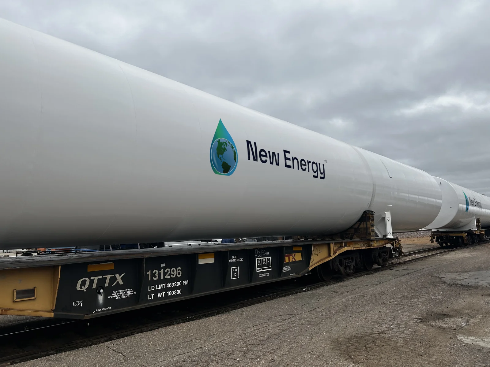 White GreenER™ LNG storage tanks carrying the New Energy logo, loaded on a rail flatcar