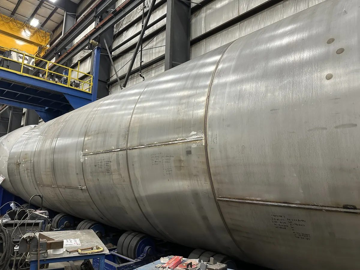 Mid-fabrication GreenER LNG tank shell at Chart Industries — bare stainless wall, overhead crane visible above